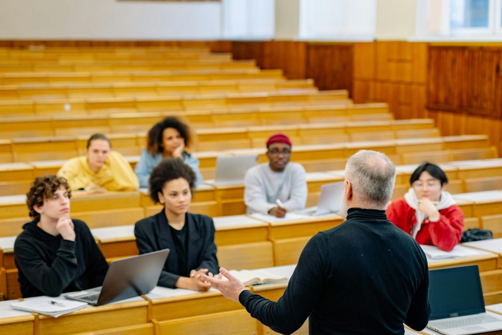 Students attending a lecture in a university classroom with an engaged professor.